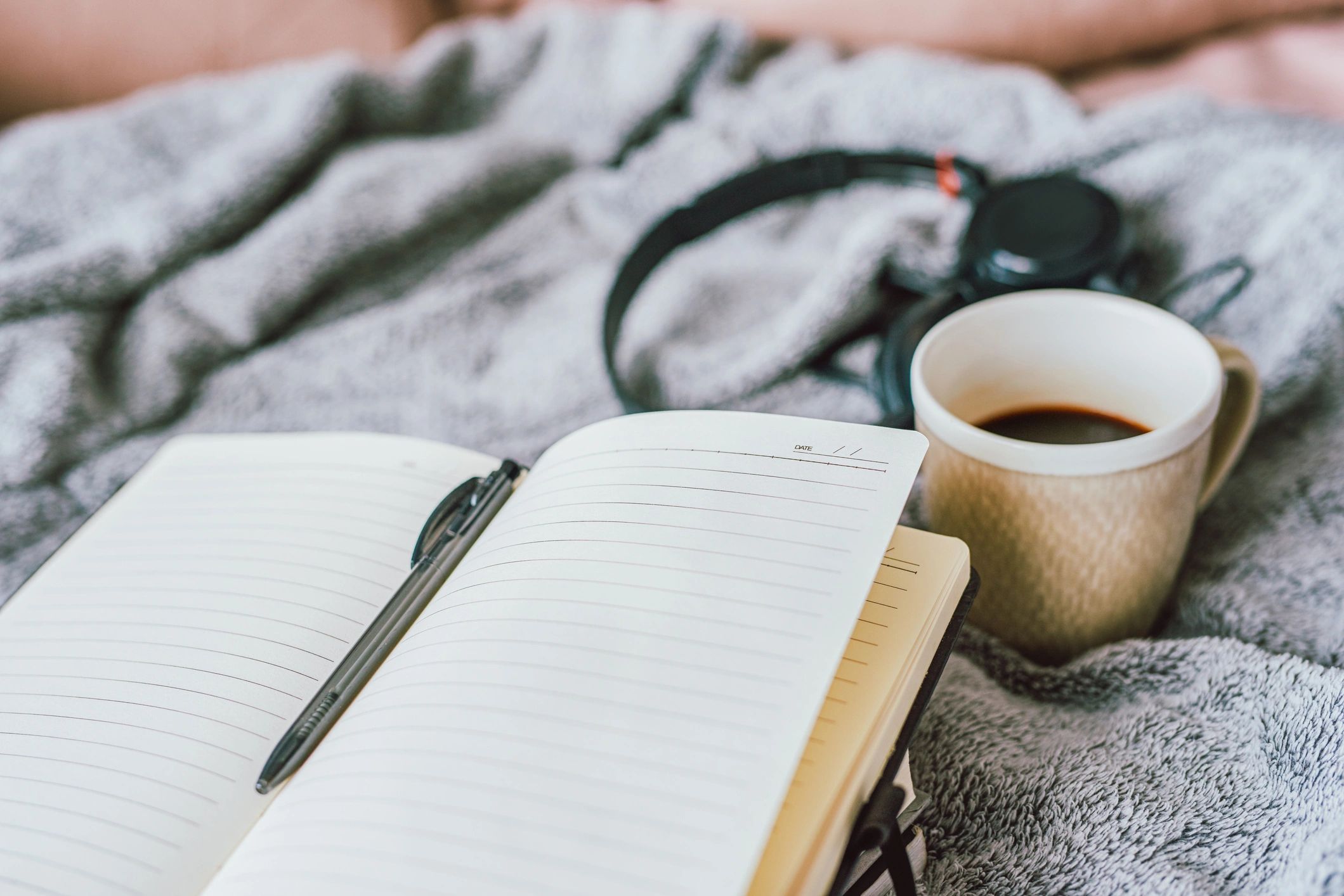 Notebook and coffee on a bed, travel writing setup
