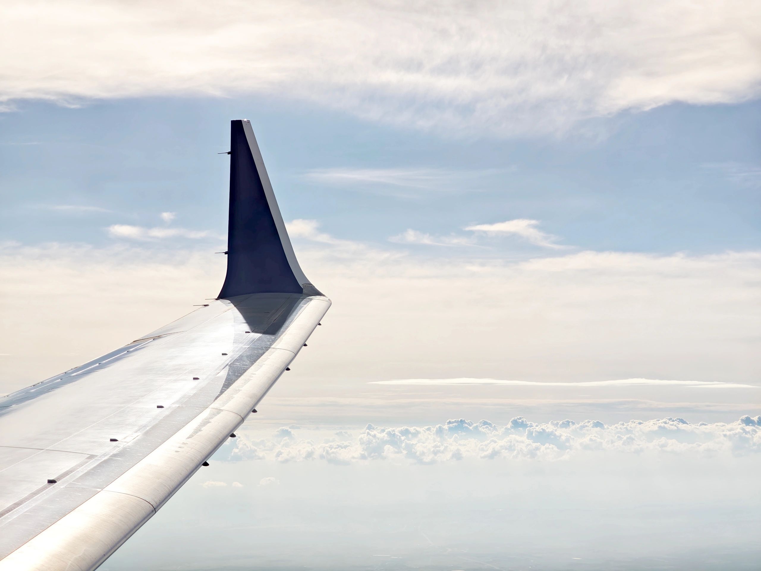 Airplane wing above bright clouds